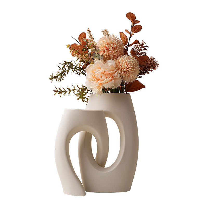 White ceramic loop vase pair with decorative flowers; styling props shown