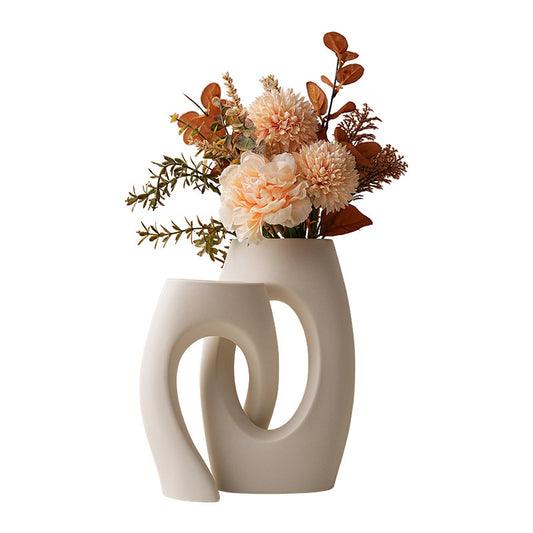 White ceramic loop vase pair with decorative flowers; styling props shown